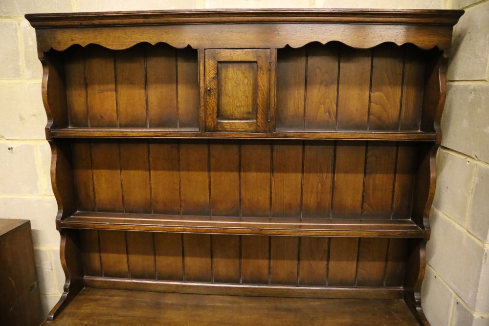 A small Georgian style reproduction oak dresser, having shelved boarded back, shaped apron and pot shelf, width 137cm, depth 44cm, heig